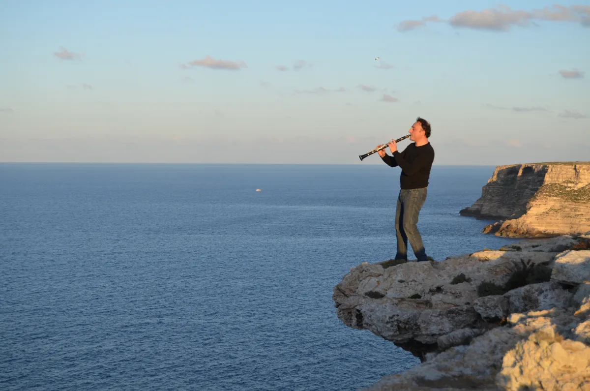 Un clarinettista sulla scogliera, al tramonto – Scatto artistico – Puglia (costa)